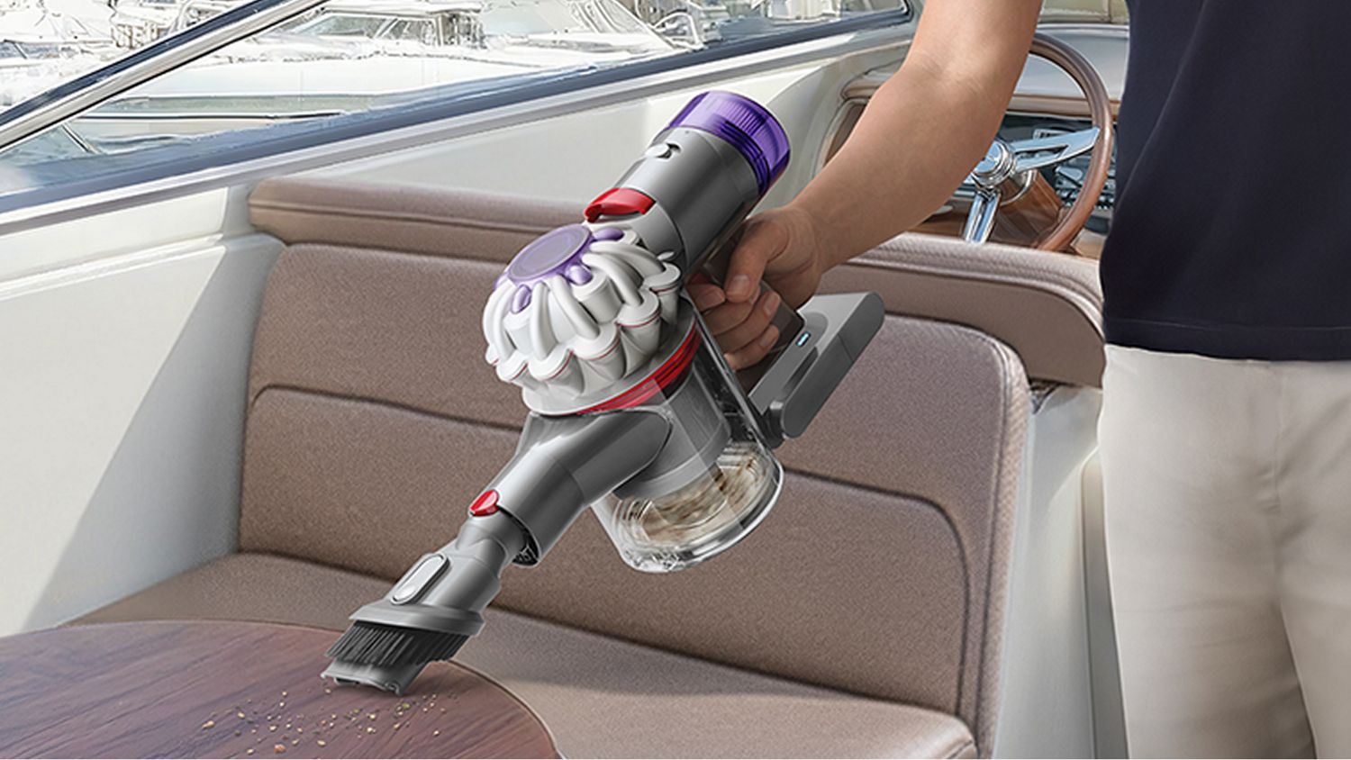 The Dyson Car+Boat handheld vacuum with the Combinationton tool cleaning mess from a table on a boat.